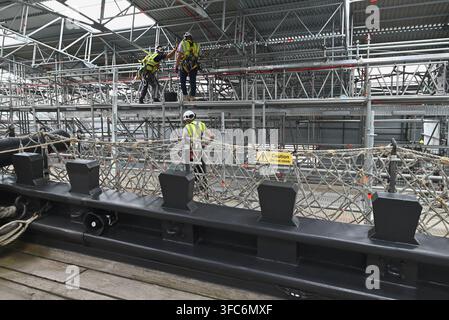 Arbeiter auf Gerüsten, die die HMS Victory umgeben, tragen Warnwesten und Schutzhelme. August 2026. Stockfoto