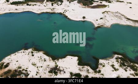 Türkisblaues Seewasser kontrastiert mit weißen Sanddünen und grünen Vegetationsflächen, gesehen von oben Stockfoto