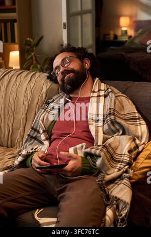 Mittelalter Mann hört Musik auf dem Smartphone zu Hause Stockfoto
