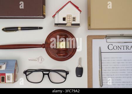 Ein Arbeitsbereich für Anwälte mit einem Richterhammer, einem Hausmodell und rechtlichen Dokumenten, die Immobilienrecht und Rechtspraxis symbolisieren Stockfoto