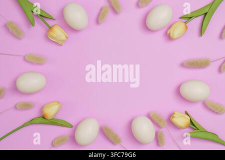Elegante weiße Eier umgeben von gelben Tulpen auf einem weichen rosa Hintergrund, ideal für Ostereier-Dekorationen Stockfoto