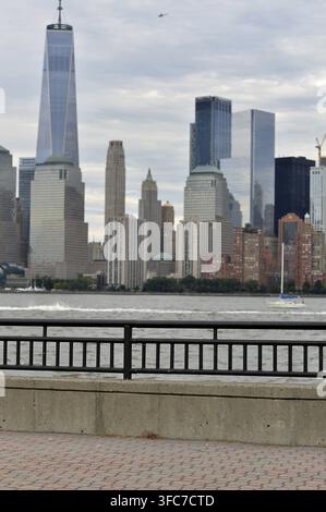 Promenade-Zaun im Hochformat lenkt die Aufmerksamkeit auf die Wolkenkratzer von Manhattan, Moody Clouds, New York Stockfoto