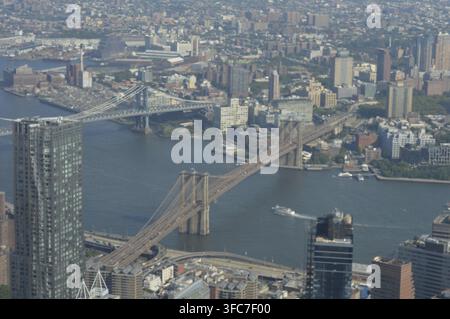 Luftbild der Brooklyn Bridge, die Manhattan mit dem sonnenbeschienenen East River, einer belebten Straße und dichtem New York verbindet Stockfoto