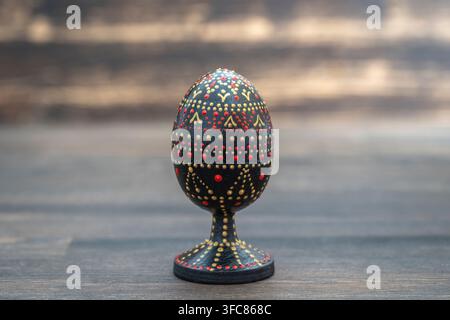 Farbenfrohes handgefertigtes Osterei auf Holzuntergrund. Handbemalte Ostereier mit Acrylfarben, Handarbeit, Punktmalerei, Nahaufnahme, Ukraine Stockfoto