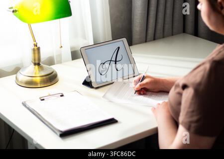 Schreibschrift-Training. Frau schreibt präzise in einem Schreibheft mit einem Stift. Erwachsene übt Kursivschrift in einem Propisi-Notizbuch. Globale Hinwendung zu analogen Gewohnheiten Stockfoto