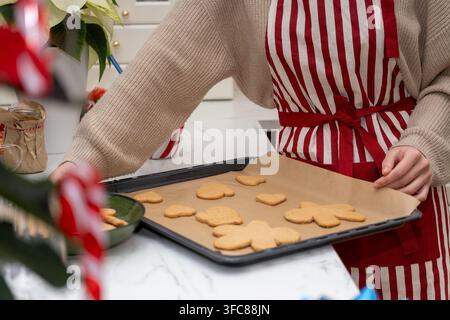 Frau trägt ein Backblech mit frisch gebackenen Lebkuchen für Weihnachten zu Hause Stockfoto