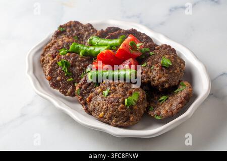 Traditionelle türkische Islama Kofte oder Akçaabat Kofte, serviert mit in Soße getränktem Brot, gegrillten Paprika und Tomaten Stockfoto