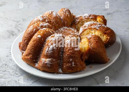 Frisch gebackener Bundt-Kuchen mit Puderzucker auf einem weißen Teller Stockfoto