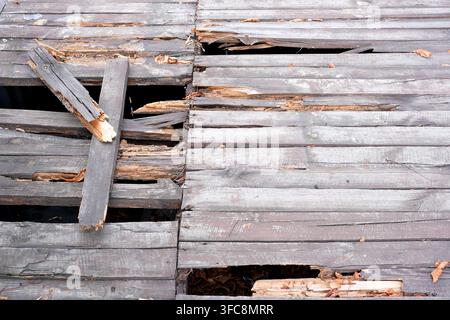 Beschädigter und zerbrochener verwitterter Holzsteg mit großen Löchern und verrotteten Planken. Hochwinkel-Ansicht von einem ruinierten alten Holzdeck oder Brückenpfeiler Stockfoto