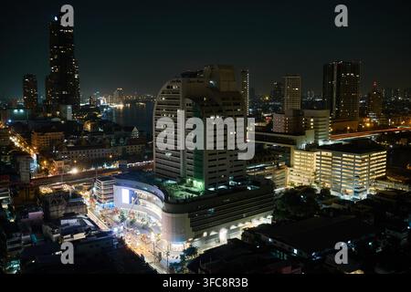 Bangkok-Skyline von Bang Rak bei Nacht, gesehen vom Lebua-Hotel in Bangkok, Thailand, mit dem beleuchteten Central Bangrak-Einkaufszentrum unten. Stockfoto