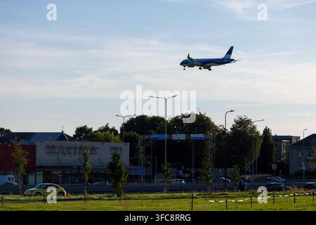 Vilnius, Litauen - 09. August 2026: Blick auf ein Passagierflugzeug, das zur Landung am Vilnius International Airport anfliegt, mit einem gelben Auto auf der R Stockfoto