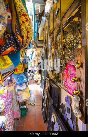 Phnom Penh, Kambodscha – 13. Februar 2020: Blick auf einen schmalen Marktgang in Phnom Penh mit bunten Taschen, dekorativer Metallwandkunst und verschiedenen g Stockfoto