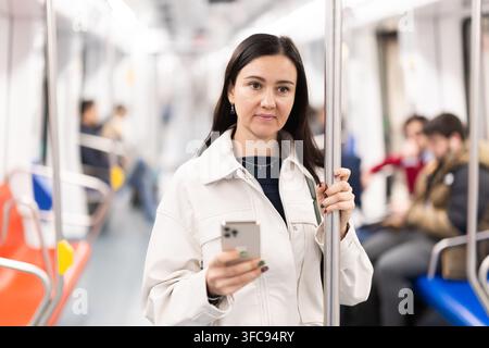 Weibliche Passagiere reisen im U-Bahn-Auto und nutzen das Mobiltelefon, um in sozialen Netzwerken zu kommunizieren Stockfoto