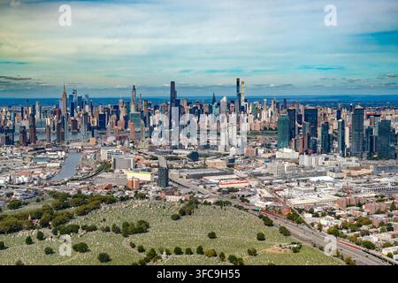 Hohe Luftaufnahme, die über das Viertel Queens und den Calvary-Friedhof im Vordergrund bis zur dichten Skyline von Midtown Manhattan schaut Stockfoto