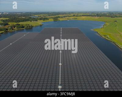 Luftaufnahme einer großen schwimmenden Solarfarm, die auf einem See installiert ist, umgeben von grünen Feldern und ländlicher Landschaft in den Niederlanden. Stockfoto