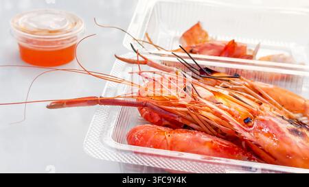 Fettige, gegrillte Garnelen in einer durchsichtigen To-Go-Box Stockfoto