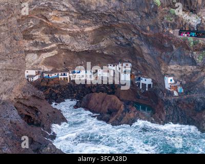 Luftaufnahme von Poris de Candelaria, einem Dorf aus weißen Häusern, das in einer riesigen vulkanischen Meereshöhle eingebettet ist, mit brandenden Wellen gegen dunkle Felsen in der Stockfoto