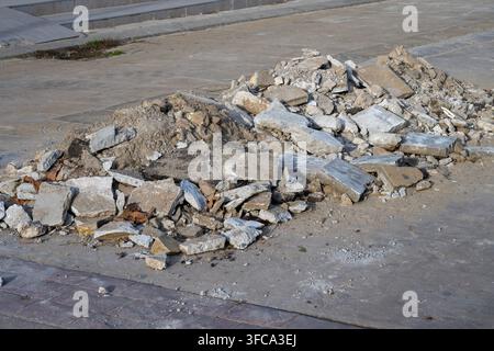 Ein Haufen gebrochenen Betons, Schutt und Bauschutt liegt verstreut auf einem gepflasterten Boden. Stockfoto