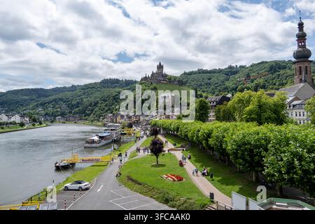 Cochem Deutschland - 2. Aug. 25: Die Reichsburg Cochem überblickt die Mosel, Boote, die Promenade und die farbenfrohen Stadtgebäude in Deutschland. Stockfoto