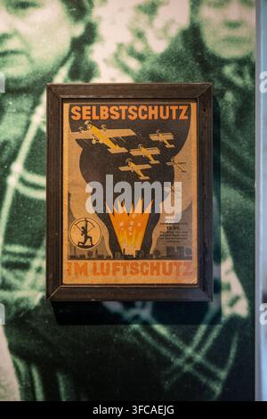Remagen, Deutschland - 9. Aug. 25: Gerahmter historischer deutscher Luftschutz-Plakat zur Selbstschutzausbildung im Friedensmuseum Brücke in Remagen in Rheinland Stockfoto