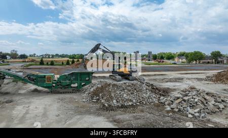 Luftbild eines Baggers und einer Betonzerkleinerungsmaschine, die Schutt auf einer Baustelle in Ronks, Pennsylvania, Vereinigte Staaten, verarbeiten. Stockfoto