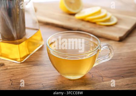 Kräutertee für Wohlbefinden und einen gesunden Lebensstil, heißes Getränk in einer Glastasse mit Zitronenscheiben auf einem Holztisch Stockfoto