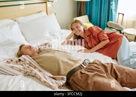 Glückliches Paar entspannt sich auf dem Bett im Hotelzimmer während des Urlaubs Stockfoto