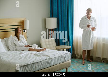 Glückliches Paar in Bademänteln entspannt in einem Luxushotelzimmer Stockfoto