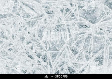 Detaillierte Nahaufnahme von rissigem, geschichtetem Eis, das durchscheinende Kristalle und geometrische Muster in kalten Blautönen zeigt. Ein vielseitiger Winterhintergrund geeignet Stockfoto