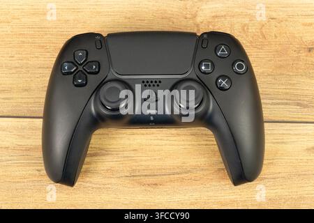 Schwarzer Sony PlayStation 5 DualSense-Drahtloser Controller, der auf einer Holzoberfläche ruht Stockfoto