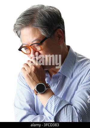 Nachdenklicher koreanischer Senior-Manager blickt in einem Nahaufnahme-Studio-Porträt nach unten Stockfoto