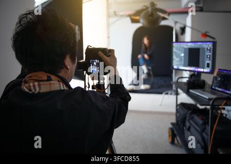 Senior koreanische Fotografin, die ein Porträt einer weiblichen Model in einem professionellen Studio aufnimmt Stockfoto