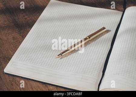Ein Notizbuch mit Rascherseiten liegt auf einem Holztisch offen. Ein Stift liegt daneben und lädt zum Schreiben ein. Das Sonnenlicht erhellt die Szene und deutet an Stockfoto