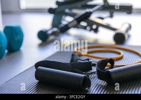 Eine Sammlung von Fitnessgeräten für ein Heimtraining, darunter ein Stepper, Gewichte und Widerstandsbänder, die auf einer Matte ausgelegt sind Stockfoto