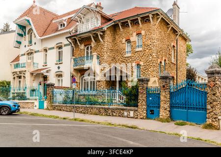 Eine Jugendstil-Villa aus Bruchstein mit einem türkisfarbenen Metalltor und einem geschwungenen Balkon in der Rue Félix Faure in Nancy, Grand Est, Frankreich. Stockfoto