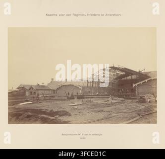 Kaserne für ein Infanterieregiment in Amersfoort, Fotografie, Foto, gelblich-braun, auf Karton, mit Titel oben und Beschreibung unten. Inschrift, mo: '..Bataillonskaserne Nr. 3..', Fotograf: P. Oosterhuis, Amersfoort, 1892, Karton, Papier, Fotografie, Paste, Höhe 48,5 cm x Breite 66 cm, Niederlande, Periode, 1875 - 1900., Eine sepiafarbene Szene einer Baustelle, die mehrere Backsteingebäude und eine große eiserne Rahmenkonstruktion eines gebogenen Daches zeigt, die im Bau ist, mit Gerüsten und Holzbalken, die den teilweise gebauten Rahmen umgeben; der Boden davor ist schlammig mit verstreuten Stockfoto