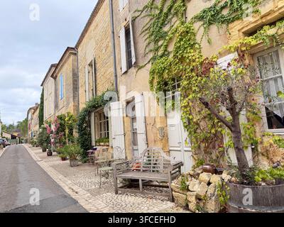 BEAUMONT, FRANKREICH – 20. AUGUST 2026: Historische französische Dorfstraße mit traditionellen Steinhäusern, weißen Fensterläden, Efeu und alten Steinfassaden Stockfoto