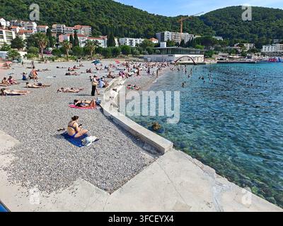 Ein lebhafter Kieselstrand in Dubrovnik im Sommer, an dem sich vielfältige Touristen an der Adriaküste sonnen und entspannen. Stockfoto