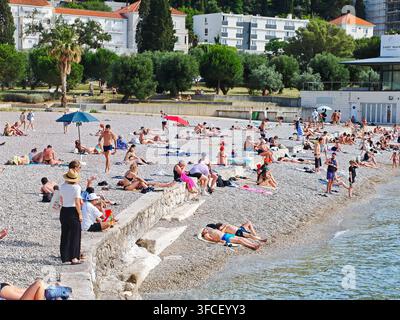 Ein lebhafter Kieselstrand in Dubrovnik im Sommer, an dem sich vielfältige Touristen an der Adriaküste sonnen und entspannen. Stockfoto