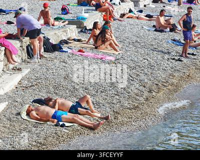Ein lebhafter Kieselstrand in Dubrovnik im Sommer, an dem sich vielfältige Touristen an der Adriaküste sonnen und entspannen. Stockfoto