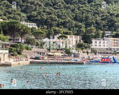 Ein lebhafter Kieselstrand in Dubrovnik im Sommer, an dem sich vielfältige Touristen an der Adriaküste sonnen und entspannen. Stockfoto