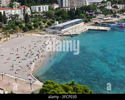 Ein lebhafter Kieselstrand in Dubrovnik im Sommer, an dem sich vielfältige Touristen an der Adriaküste sonnen und entspannen. Stockfoto