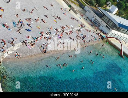 Ein lebhafter Kieselstrand in Dubrovnik im Sommer, an dem sich vielfältige Touristen an der Adriaküste sonnen und entspannen. Stockfoto