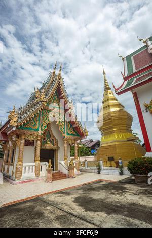 Dok kham tai, Phayao, Thailand - 27. August 2026: Wat Don Lek, goldener Chedi und Ordinationshalle mit gestuftem Dach und Naga-Fialen Stockfoto