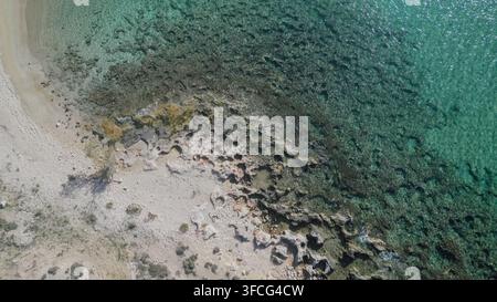 Luftaufnahme von oben eines sandigen Strandes mit felsiger Küste und klarem türkisfarbenem Meerwasser an der Küste der Insel Kreta in Griechenland, horizontale Stockfoto. Stockfoto