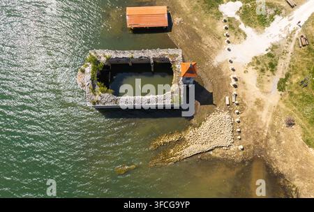 Luftaufnahme der versunkenen Kirche St. Nikolaus, die teilweise im Mavrovo-See versunken ist, mit einem grasbewachsenen Ufer und klarem Wasser in Mavrovo, Gemeinde Stockfoto