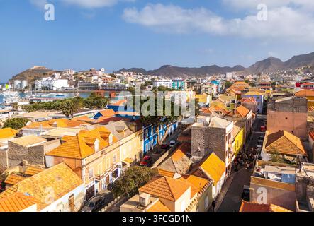 Luftaufnahme der farbenfrohen historischen Gebäude und orangefarbenen Dächer, mit dem Hafen und den Bergen im Hintergrund in Mindelo, Sao Vicente, Kap Verde Stockfoto