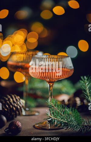 Funkelndes Rose-Cocktail serviert in einem eleganten Glas mit leuchtenden Weihnachtslichtern, Tannenzweigen und saisonalen Dekorationen für Weihnachtseinladungen, Krankenhaus Stockfoto