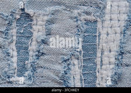 Extrem Makro-Aufnahme stark beschädigten Denimstoffs, der komplexe zerrissene Fäden und die gewebte Struktur zeigt Stockfoto