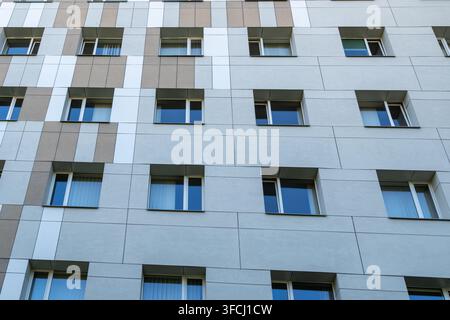 Wiederholte Reihen von Fenstern und geometrischen Fassadenpaneelen an einem modernen zeitgenössischen Gebäude Stockfoto